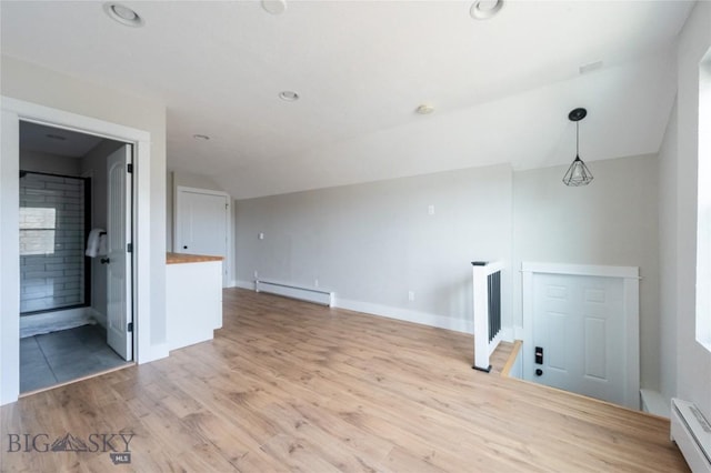 unfurnished living room featuring a baseboard heating unit, baseboard heating, light wood-style floors, lofted ceiling, and baseboards