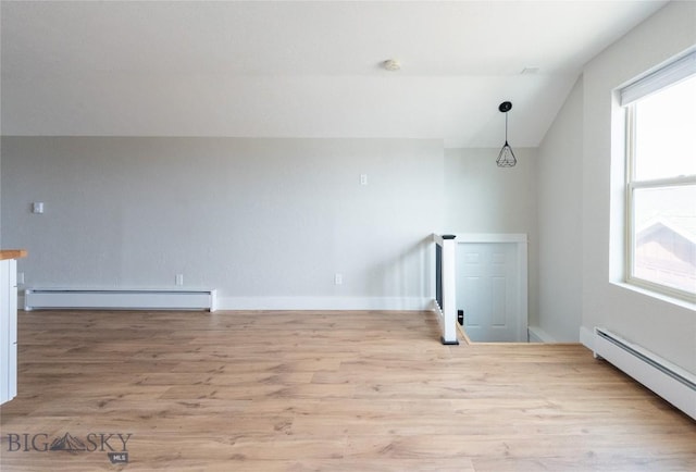 bonus room with a baseboard heating unit, lofted ceiling, wood finished floors, and baseboards