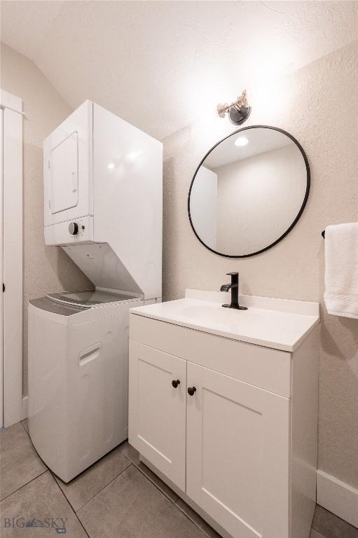 bathroom with estacked washer and dryer, vanity, and tile patterned floors