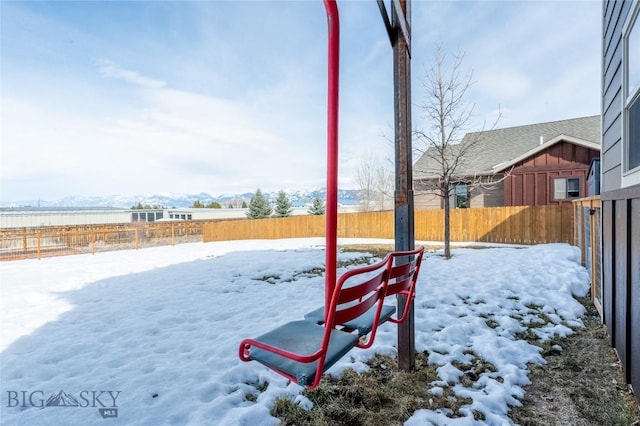 yard layered in snow featuring a fenced backyard and a mountain view