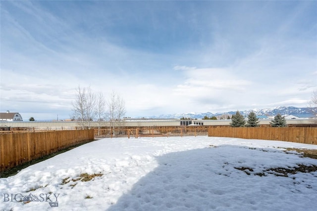 yard layered in snow with fence and a mountain view