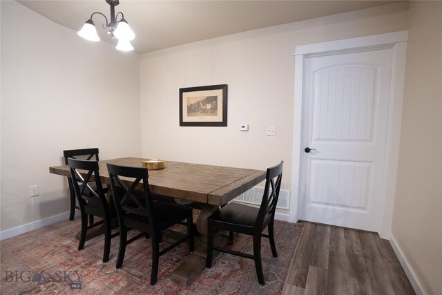 dining room with a chandelier, wood finished floors, and baseboards