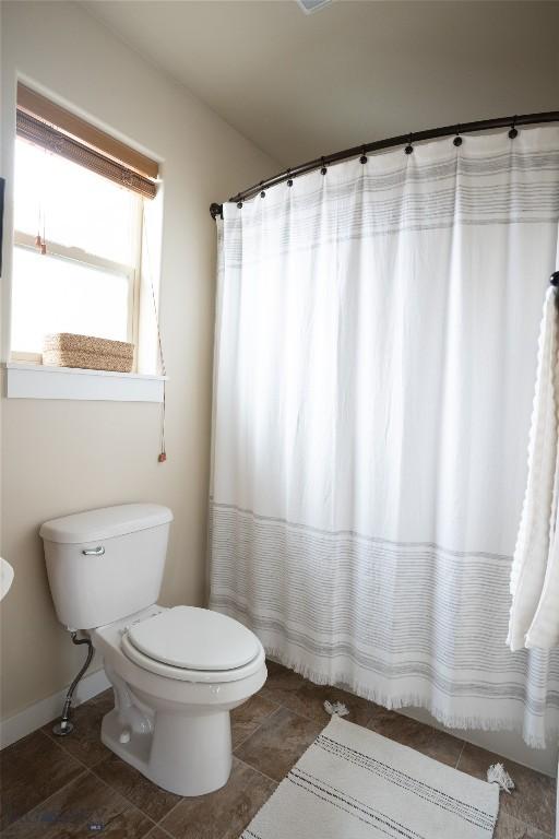 bathroom featuring toilet, tile patterned flooring, and baseboards