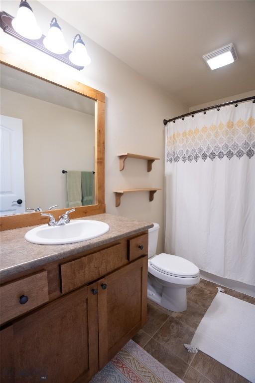 full bathroom featuring toilet, tile patterned flooring, vanity, vaulted ceiling, and curtained shower