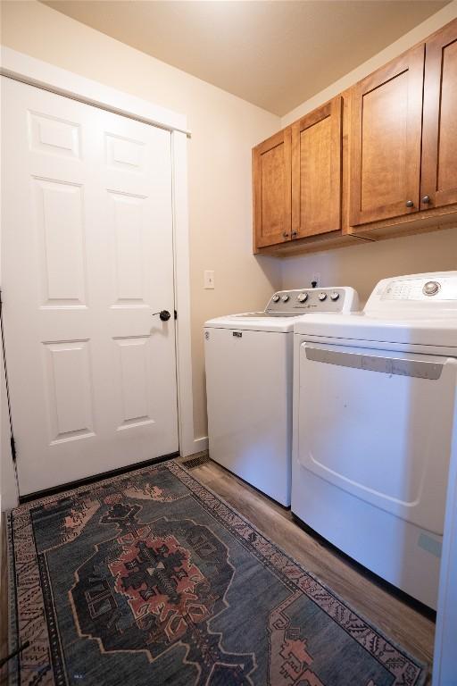 laundry room with independent washer and dryer, cabinet space, and light wood-style floors