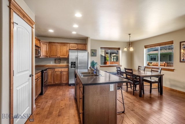 kitchen featuring stainless steel appliances, a sink, recessed lighting, a kitchen island with sink, and a kitchen breakfast bar