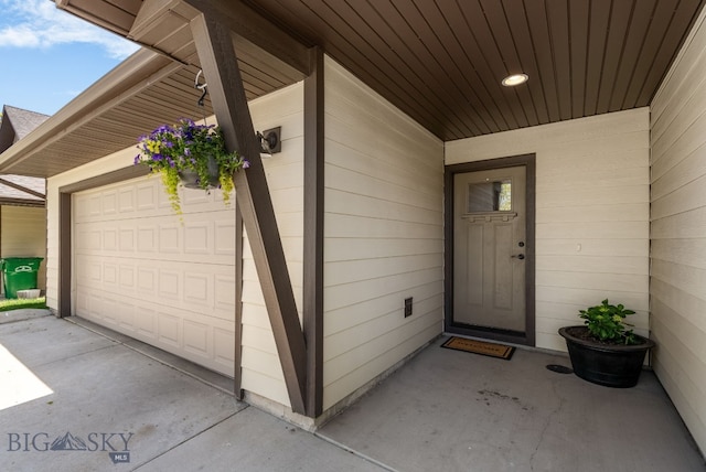 view of exterior entry with an attached garage and concrete driveway