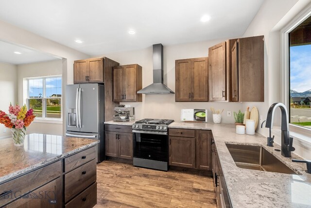 1650 Windrow, Bozeman, MT 59718 - kitchen with appliances with stainless steel finishes, wall chimney range hood, a sink, light stone countertops, and light wood-style floors