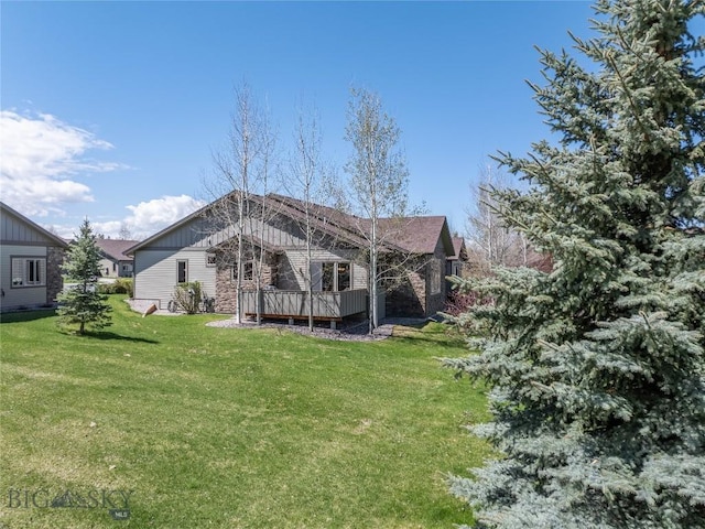 back of property with board and batten siding, a lawn, and a deck