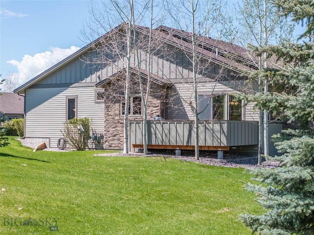 back of property with a yard, board and batten siding, and a deck