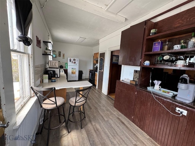 1100 Caledonia St, Butte, MT 59701 - kitchen with open shelves, freestanding refrigerator, wood finished floors, a peninsula, and a kitchen breakfast bar