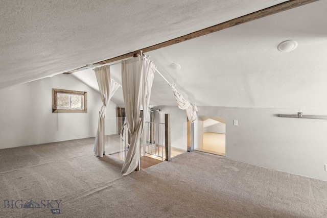 bonus room with carpet, lofted ceiling, and a textured ceiling