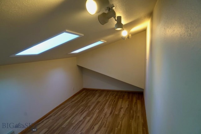 bonus room with lofted ceiling, wood finished floors, a textured ceiling, and a skylight