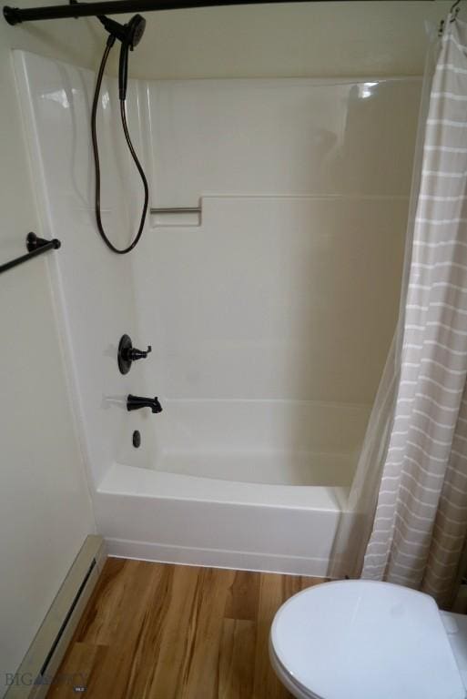 bathroom with baseboard heating, wood finished floors, and shower / tub combo