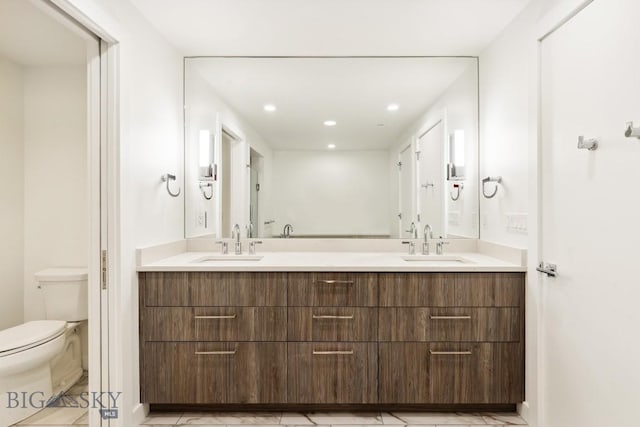 bathroom featuring toilet, double vanity, and recessed lighting