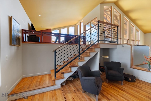 stairs with wood finished floors, baseboards, and vaulted ceiling