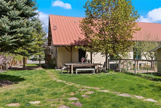 rear view of property featuring a standing seam roof, metal roof, and stucco siding