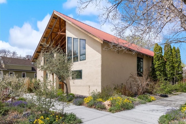 view of side of home with stucco siding and metal roof
