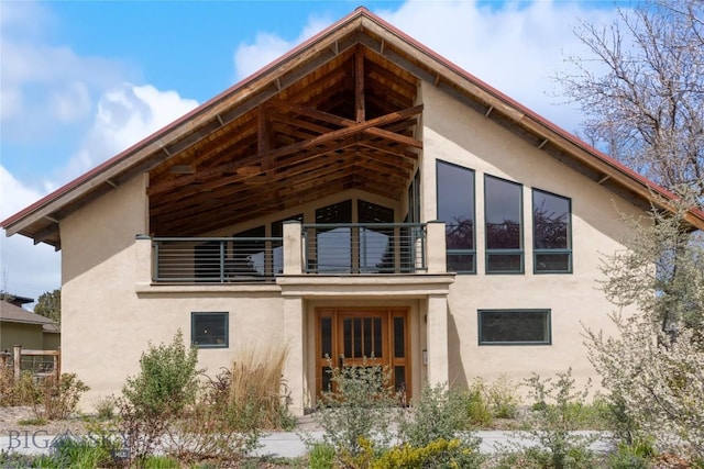back of house featuring a balcony and stucco siding