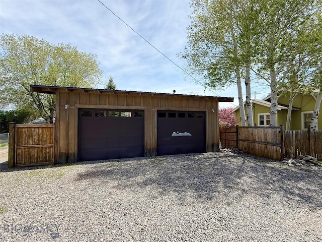 garage with gravel driveway and fence