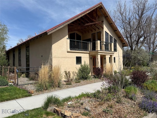 view of front of home with a balcony, stucco siding, and fence