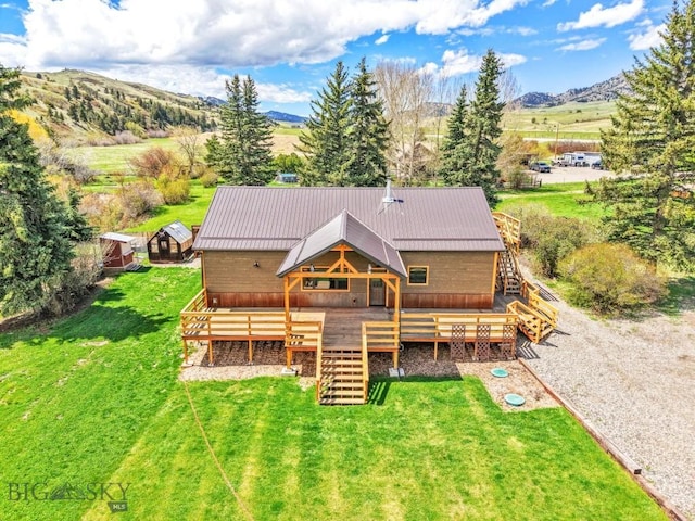 rear view of property with stairway, a deck with mountain view, a yard, and metal roof