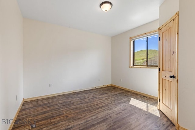 spare room featuring wood finished floors and baseboards