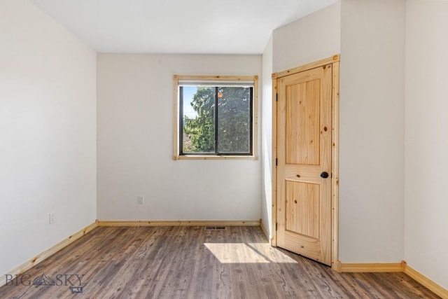 spare room featuring baseboards and wood finished floors