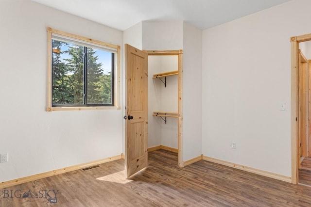 unfurnished bedroom featuring baseboards, wood finished floors, and a closet