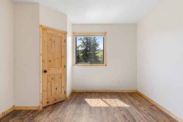 unfurnished room featuring baseboards and wood finished floors
