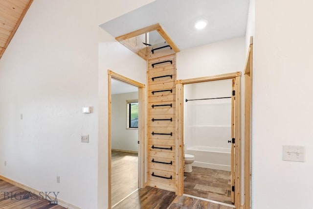 corridor featuring dark wood-type flooring and baseboards