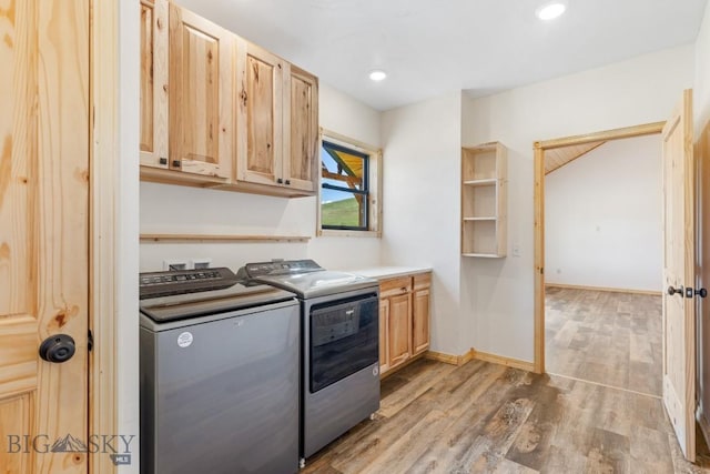 clothes washing area featuring cabinet space, washing machine and clothes dryer, light wood finished floors, and baseboards