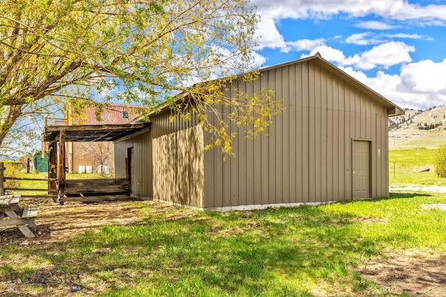 view of side of property with an outbuilding, a pole building, and a lawn