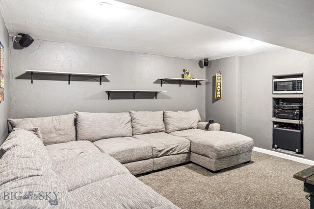 living room featuring carpet, a textured wall, and baseboards