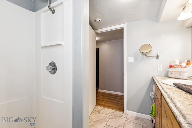 full bathroom with a shower, marble finish flooring, vanity, and baseboards