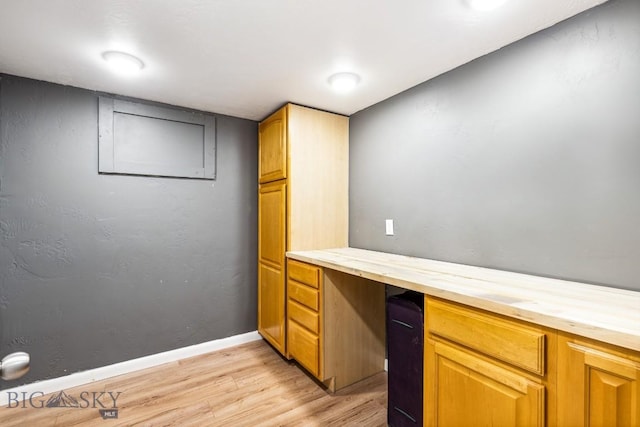unfurnished office featuring light wood-style flooring, built in study area, and baseboards