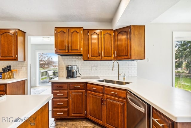 kitchen with a sink, stainless steel dishwasher, light countertops, and plenty of natural light