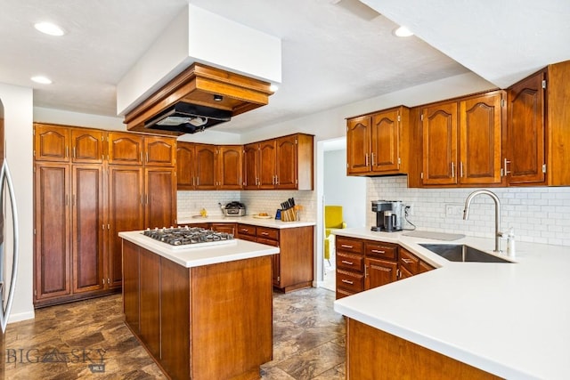 kitchen with a sink, white gas cooktop, island exhaust hood, light countertops, and backsplash