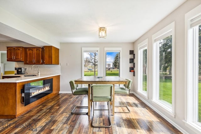 kitchen featuring dark wood finished floors, light countertops, brown cabinets, baseboards, and tasteful backsplash