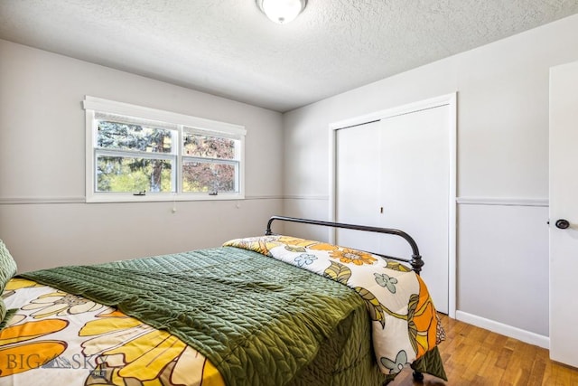 bedroom featuring wood finished floors, a textured ceiling, a closet, and baseboards
