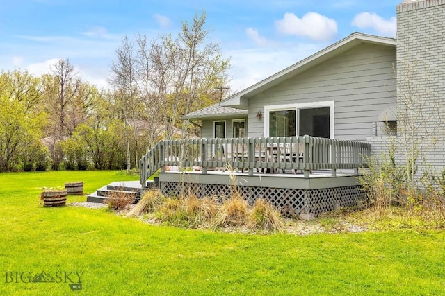 rear view of house with a yard, a deck, and a chimney