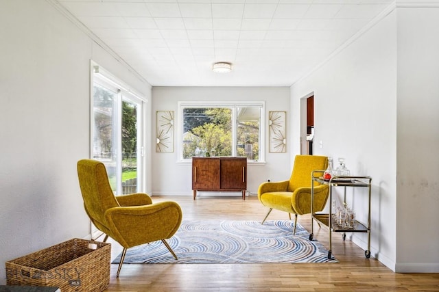 sitting room with wood finished floors, crown molding, and baseboards