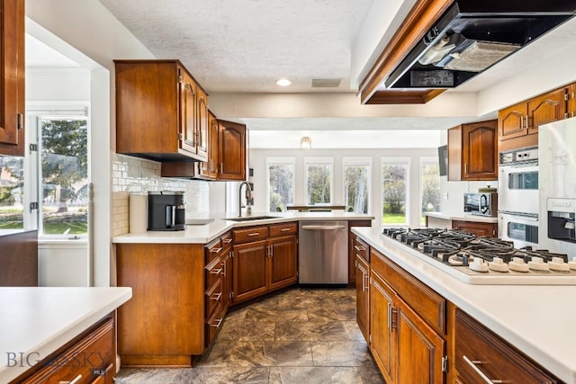 kitchen with white appliances, a sink, stone finish floors, and light countertops
