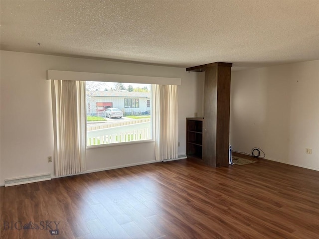 unfurnished living room with wood finished floors, a textured ceiling, and baseboards