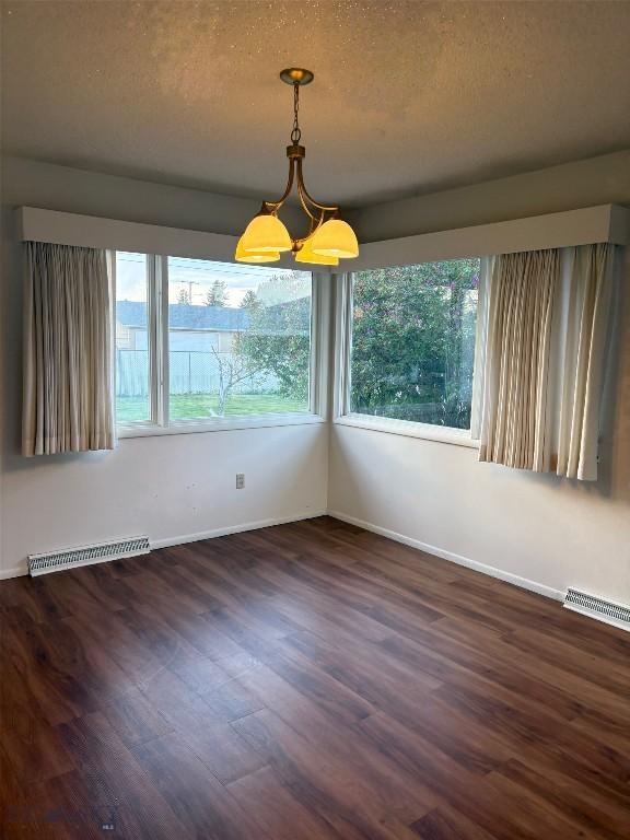 unfurnished dining area with wood finished floors, baseboards, and a textured ceiling