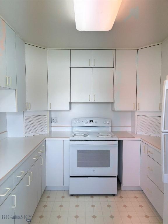 kitchen featuring white appliances, light countertops, and white cabinets