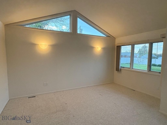 empty room with vaulted ceiling, carpet flooring, and baseboards