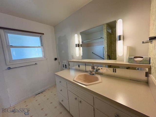 bathroom featuring baseboards, vanity, a shower, and tile patterned floors
