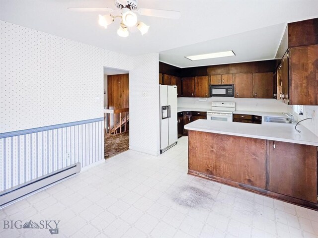 kitchen featuring white appliances, a sink, wallpapered walls, a baseboard radiator, and light countertops