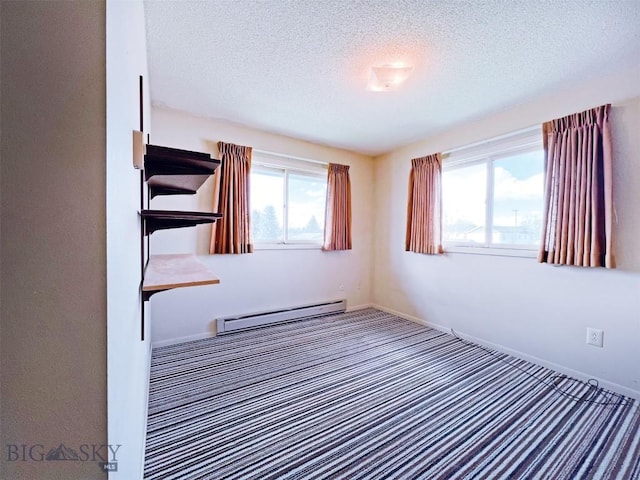 carpeted spare room featuring a baseboard heating unit, plenty of natural light, a textured ceiling, and baseboards